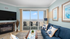 Un salon avec un téléviseur, un canapé et un balcon équipé de chaises.