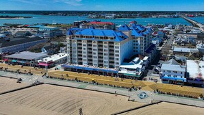 Un hôtel situé sur la côte, avec plusieurs étages, un toit bleu très visible et un emplacement en bord de mer.