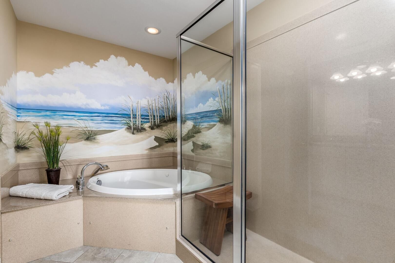 A bathroom with a glass-enclosed shower, a bathtub, and a mural of a beach scene.