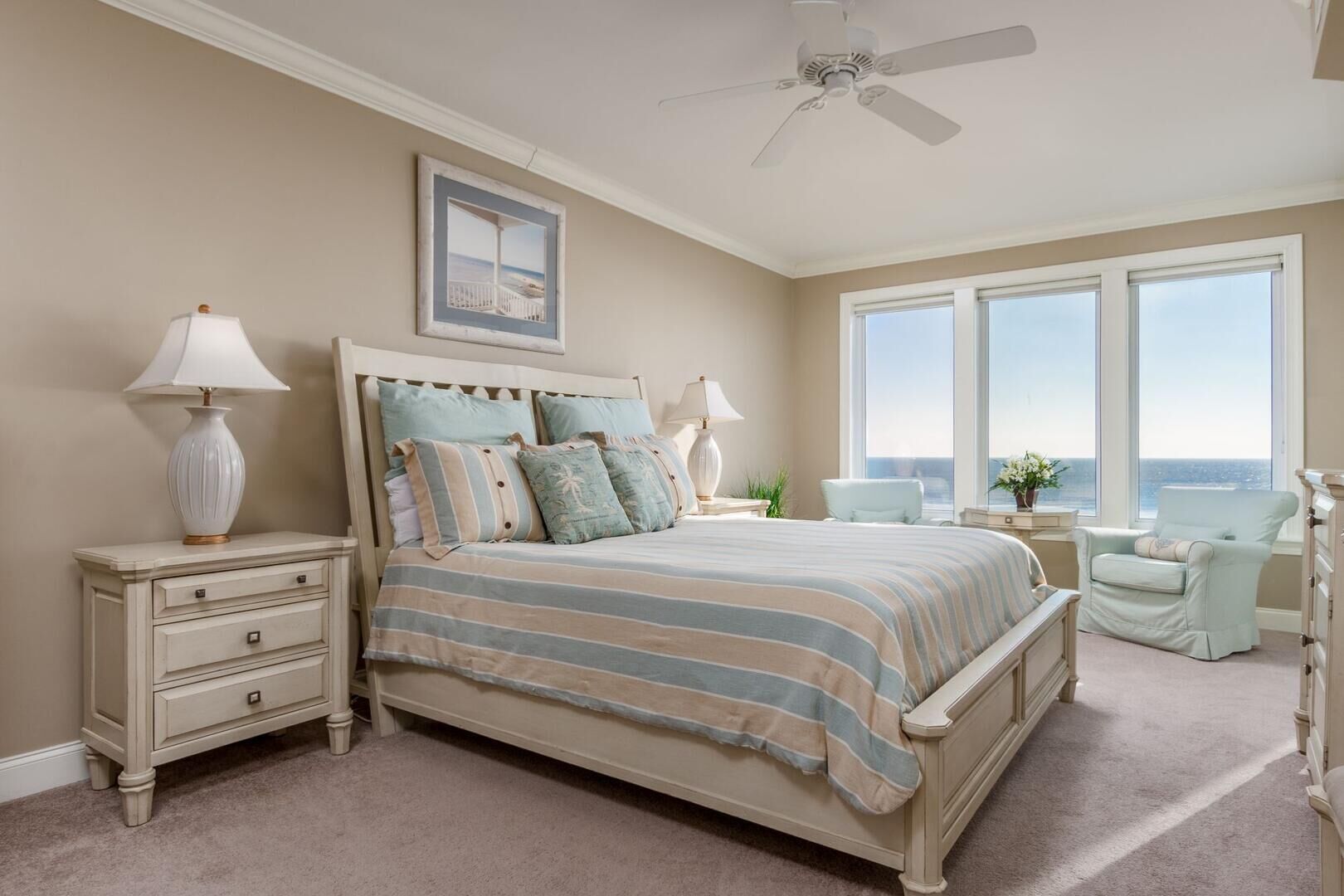 A bedroom with a large bed, two bedside tables, a nightstand, a chair, a dresser, and a ceiling fan.