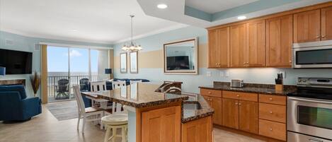 A modern kitchen with granite countertops, wooden cabinets, and stainless steel appliances.
