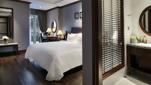 Une chambre d’hôtel moderne dotée d’un grand lit, d’un bureau, d’une coiffeuse avec un miroir et offrant une vue sur l’extérieur grâce à une porte coulissante.