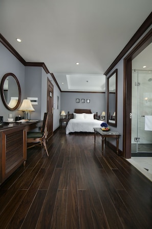 A hotel room with a large bed, a desk with a chair, a mirror, a bedside table with a lamp, and a shower area. - Hanoi La Siesta Central Hotel & Spa (Hanoi)