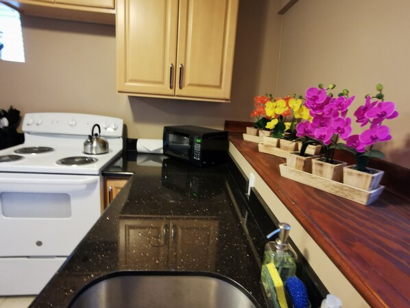 A kitchen with a stove, microwave, sink, and wooden cabinets.