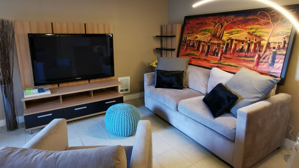 Una sala de estar moderna con un televisor de pantalla plana, un sofá y un cuadro grande en la pared.