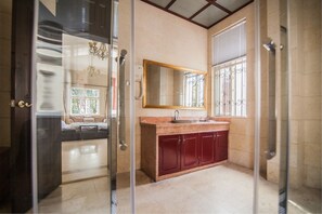 Un bany amb taulell de marbre, un lavabo, un mirall i un armari vermell.