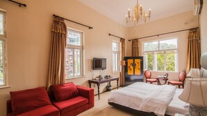 A hotel room with a bed, a red sofa, a TV, a painting, and a chandelier. - Xiamen Yunpin Hotel (Xiamen)