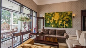 A spacious living room with a large window, a sofa, a coffee table, and a painting. - Xiamen Yunpin Hotel (Xiamen)