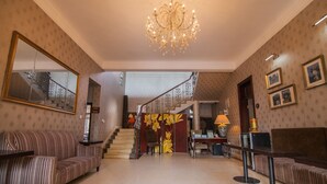 A spacious lobby with a grand chandelier, a staircase with a floral mural, and a seating area with striped sofas. - Xiamen Yunpin Hotel (Xiamen)