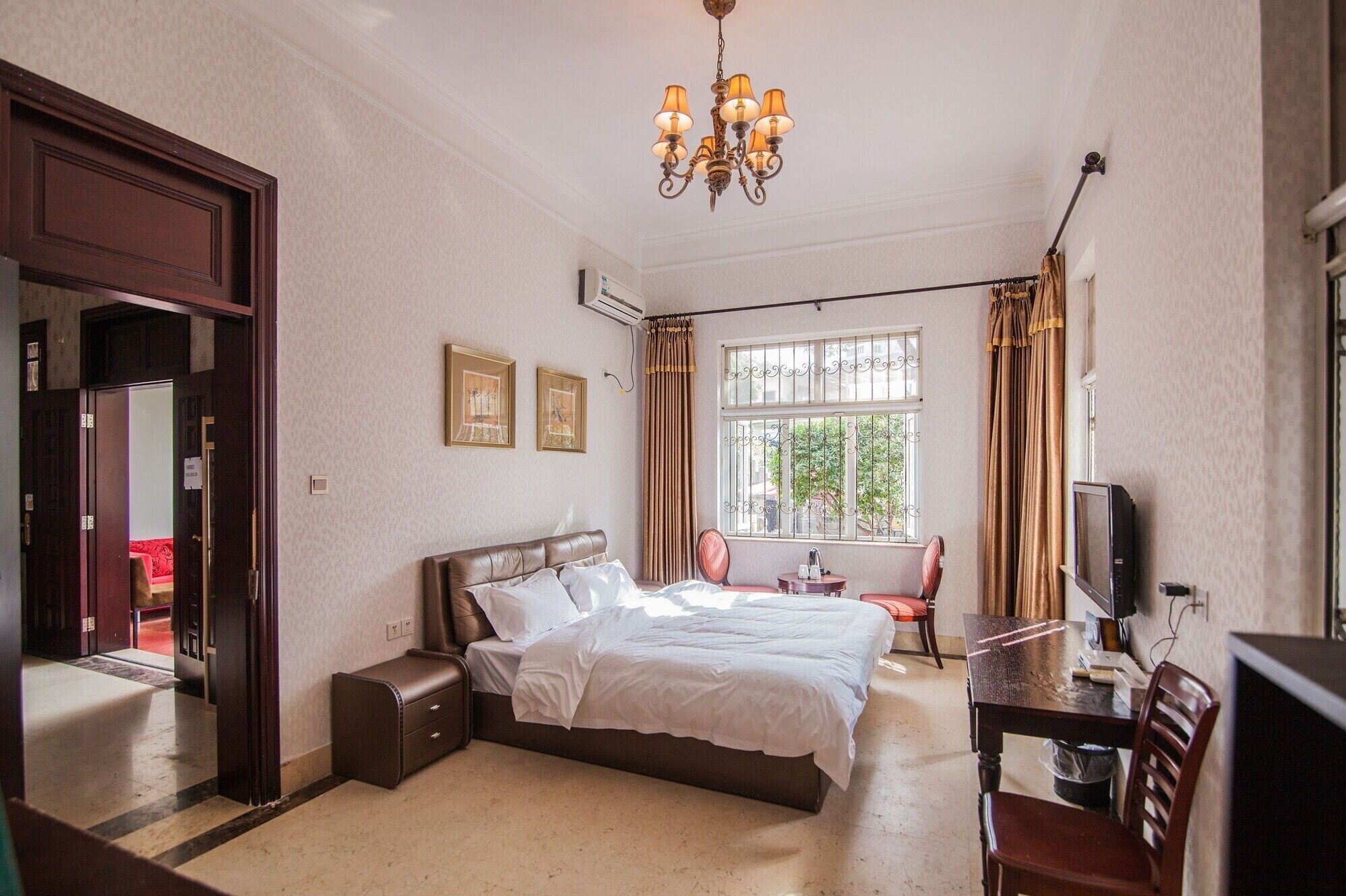 A hotel room with a large bed, a desk with a chair, a television, and a window with curtains.