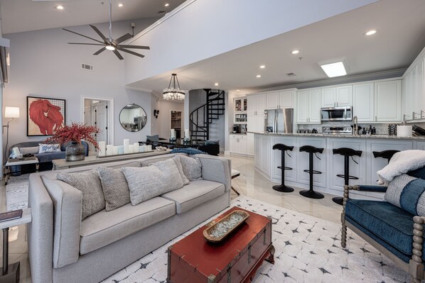 A spacious living room with a sofa, coffee table, and a staircase leading to a kitchen area.