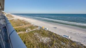 Blick auf einen Strand vom Balkon aus, mit blauem Himmel, Sandstrand und Meer.