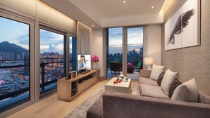 A modern living room with a large TV, comfortable seating, and a city view.