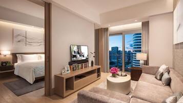 A modern hotel room with a bed, a sofa, a TV, and a large window with a city view.