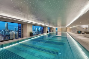 A modern indoor swimming pool with a cityscape view, a long corridor, and a seating area with a view. - Ascott Raffles City Shenzhen (Shenzhen)