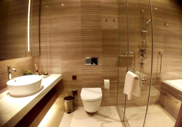 Un baño moderno con ducha de vidrio, lavamanos blanco y un inodoro.