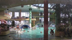 An indoor swimming pool with multiple levels, a water slide, and various aquatic features.