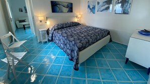 A bedroom with a bed, a desk, a chair, and artwork on the wall.