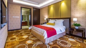 A hotel room with a large bed, a bedside table with a lamp, a wall-mounted TV, and a door leading to a bathroom. - Yangfang Shengli Hotel (Beijing)