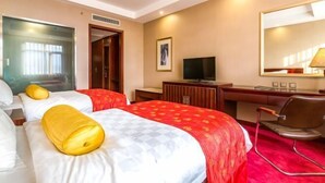 A hotel room with two beds, a desk, a television, and a mirror. - Yangfang Shengli Hotel (Beijing)
