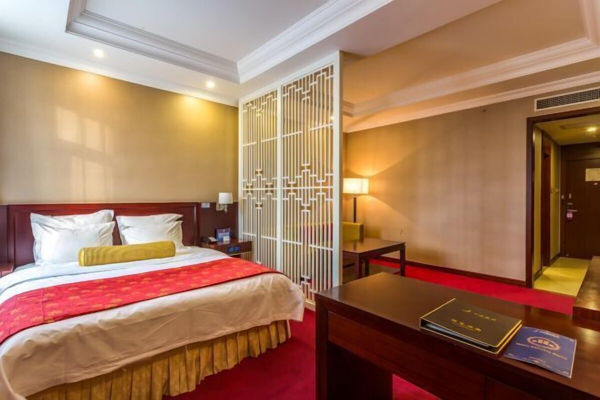 Habitación de hotel con cama, mesitas de noche, escritorio y un separador decorativo.
