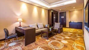 A hotel room with a sofa, a desk, a chair, a lamp, and a patterned carpet. - Yangfang Shengli Hotel (Beijing)