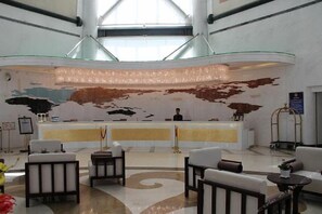 A hotel lobby with a reception desk, seating area, and a large abstract mural on the wall. - T-Longee Hotel (Beijing)