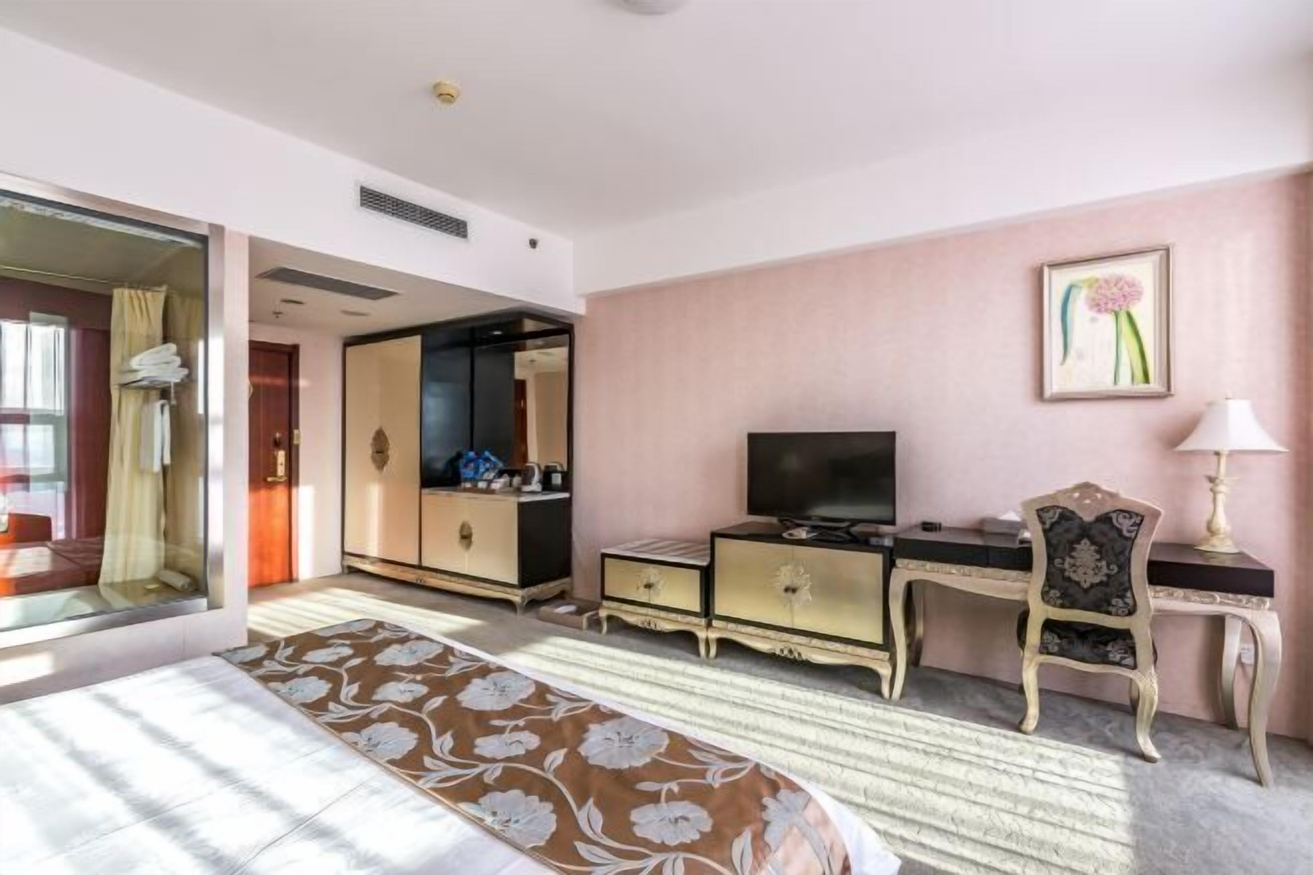 Ein Hotelzimmer mit einem Bett, einem Schreibtisch, einem Sessel, einem Fernseher und einem Spiegel.
