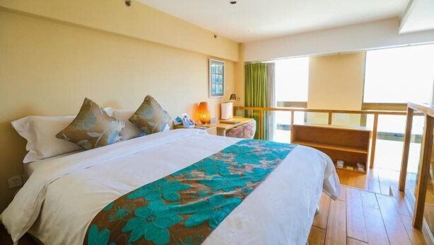 A hotel room with a bed, a nightstand, a lamp, a balcony with a railing, and a window. - T-Longee Hotel (Beijing)