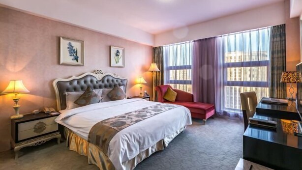 Et hotelværelse med en stor seng, sengeborde, et skrivebord og en rød sofa.