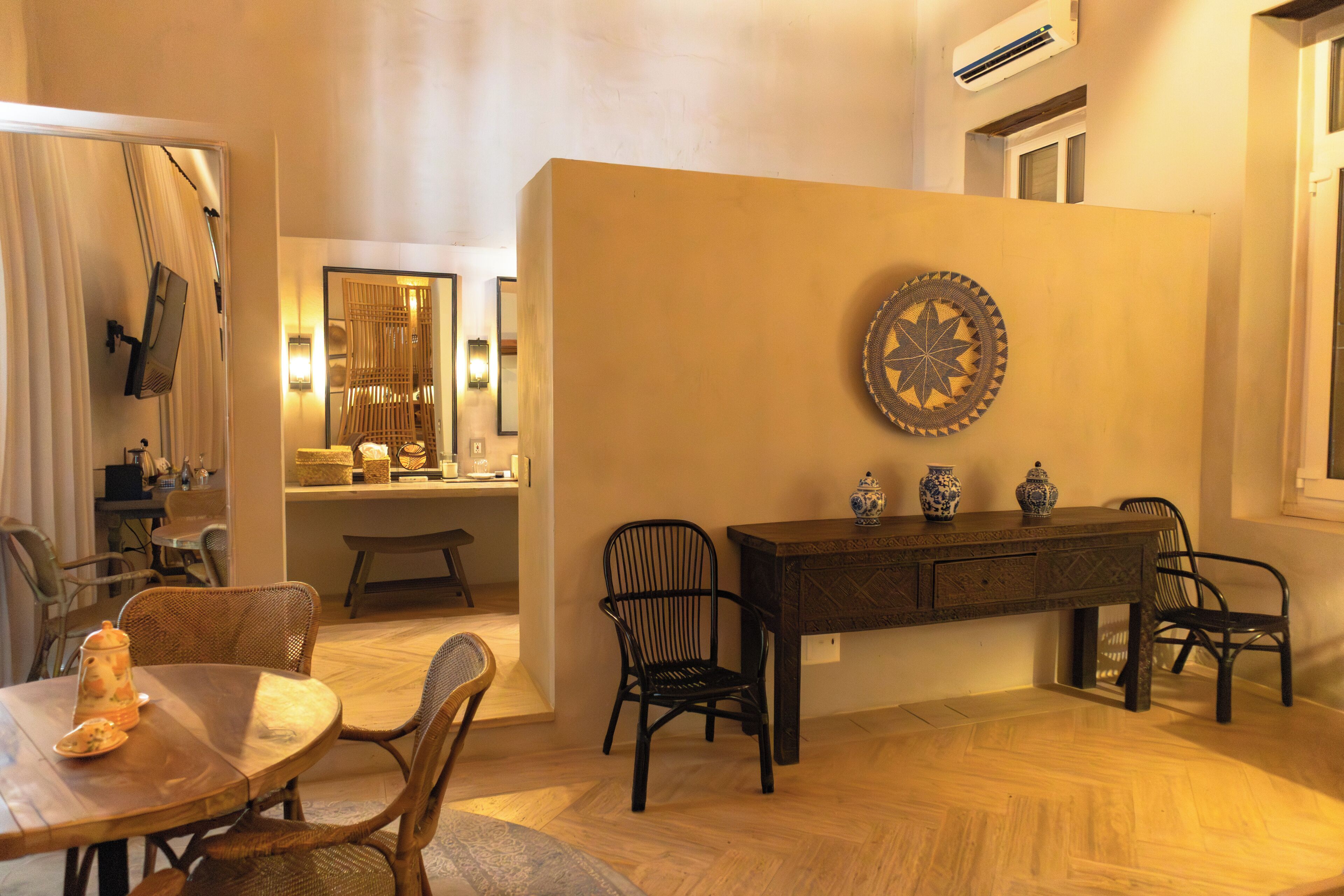 Comedor con mesa de madera, sillas, un adorno en la pared y un espejo que refleja la estancia.