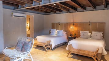 Un dormitorio con dos camas, muebles de mimbre y un techo con vigas a la vista.