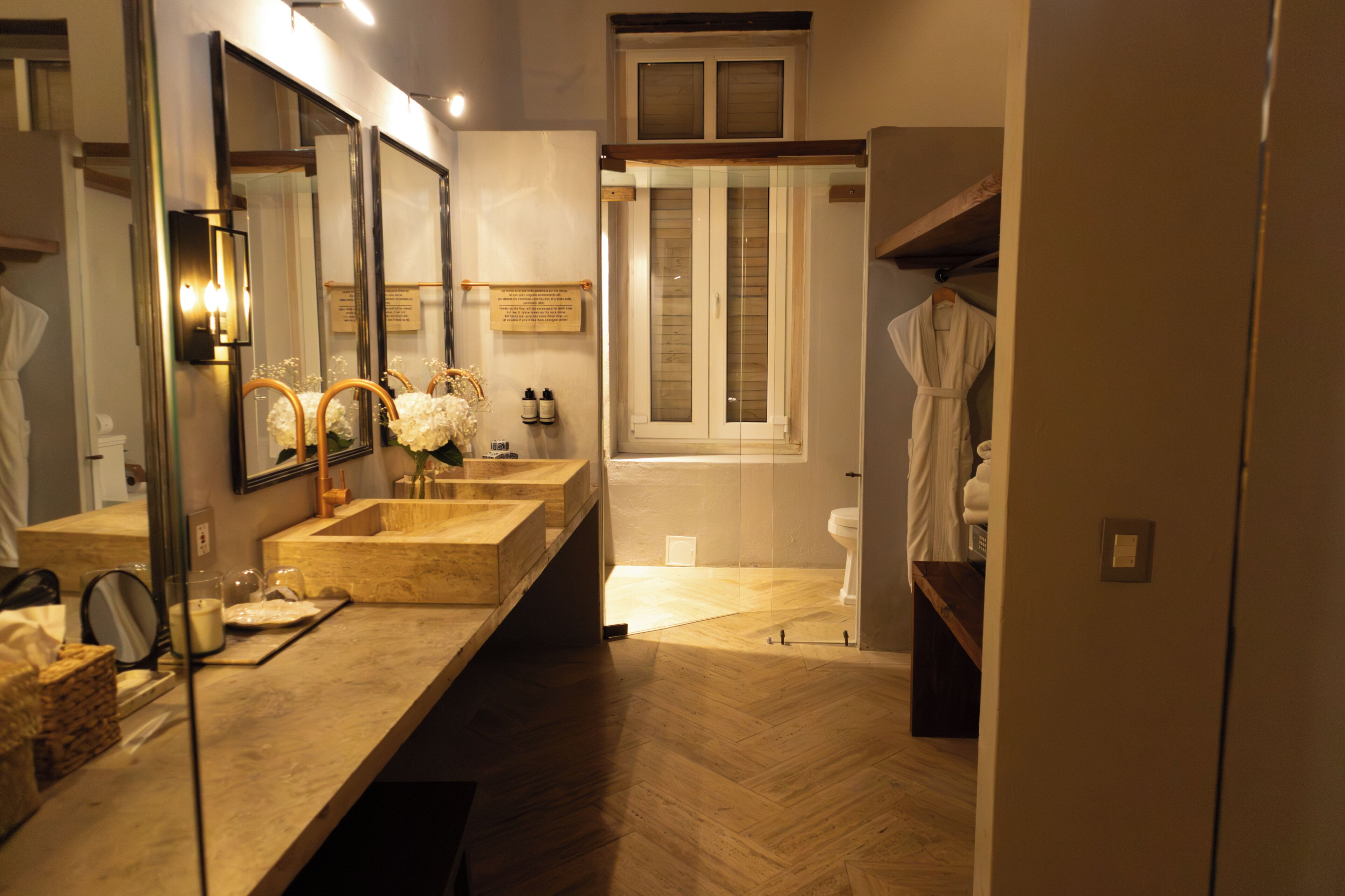 A bathroom with a large mirror, a wooden vanity, a bathtub, and a window.