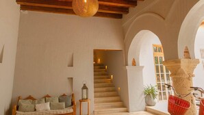 Un escalier menant à un niveau supérieur, un canapé avec des coussins, une lanterne et un panier rouge.