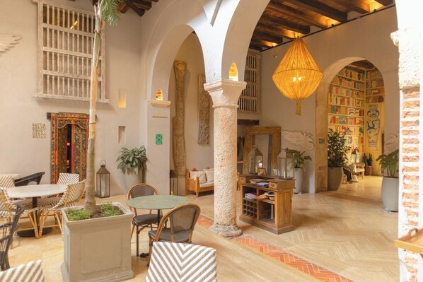 A spacious lobby with high ceilings, arched columns, and a central seating area with tables and chairs. - Hotel Casa Don Luis by Faranda Boutique, a member of Radisson Individuals (Cartagena)
