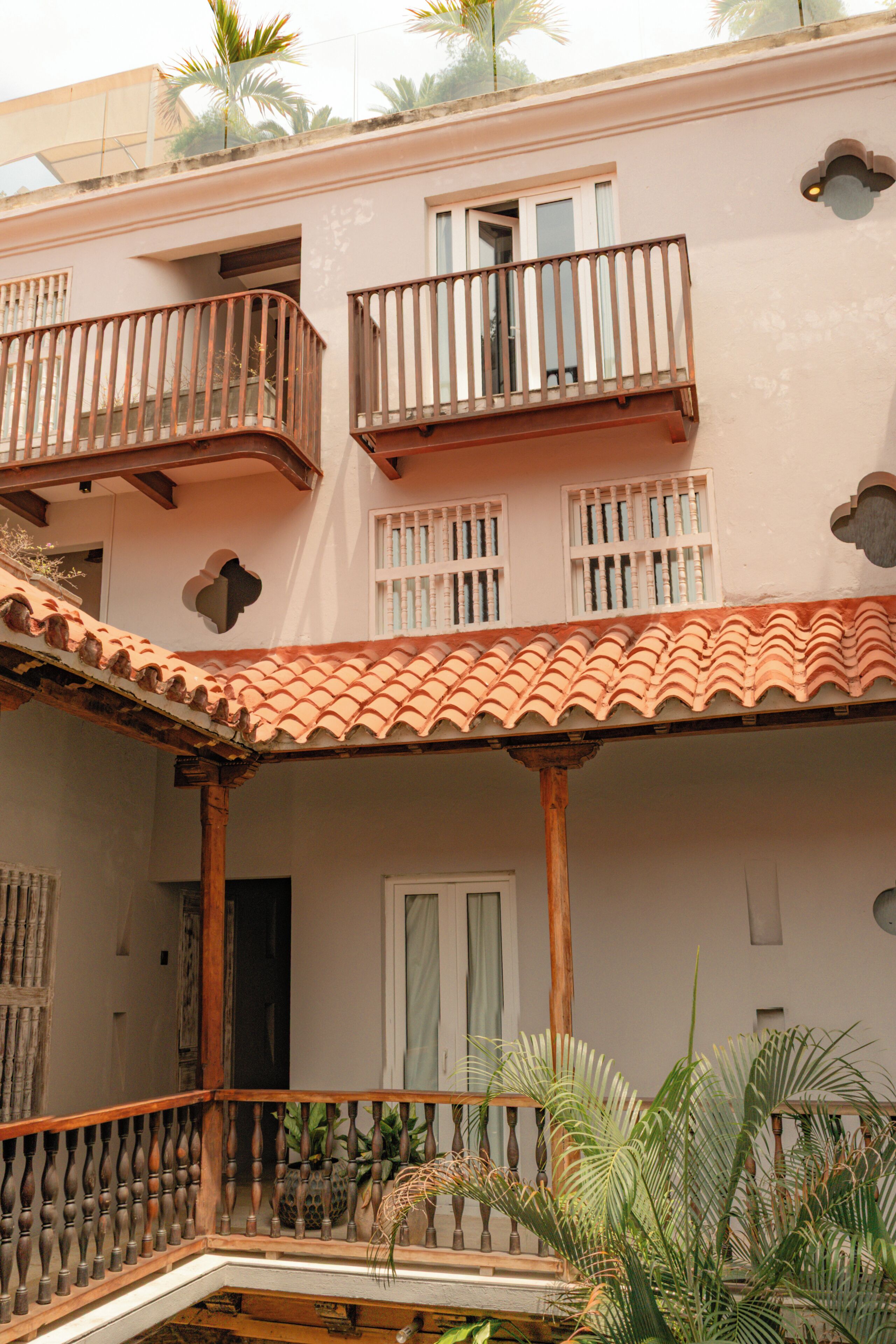 A multi-story building with balconies, a tiled roof, and a door.