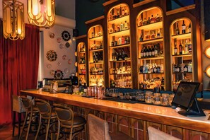 Een bar met een lange toonbank, meerdere flessenplanken en barstoelen.