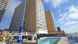 A hotel with a pool area, multiple floors, and a clear sky.