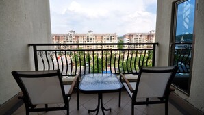 Un balcon avec deux chaises et une table, donnant sur un quartier résidentiel composé d’immeubles d’appartements.