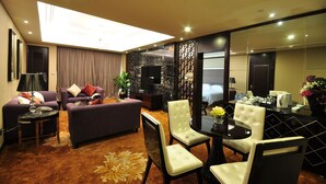 Une chambre d’hôtel moderne comprenant un espace de vie, une table à manger et une chambre à coucher séparée.