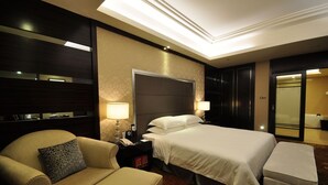 Une chambre d’hôtel avec un grand lit, une table de chevet avec une lampe, une chaise et une petite table avec un téléphone.