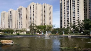 Un edificio residencial alto con una fuente en un área ajardinada.