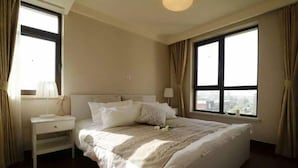 Una habitación de hotel con una cama grande, una mesita de noche y una ventana con cortinas.