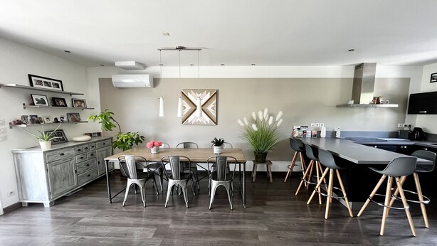 Eine moderne Küche mit Essbereich, inklusive Holztisch, Stühle und eingebautem Backofen.