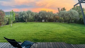 Ein Garten mit einer Holzterrasse, einer Schaukel und einer Pergola.