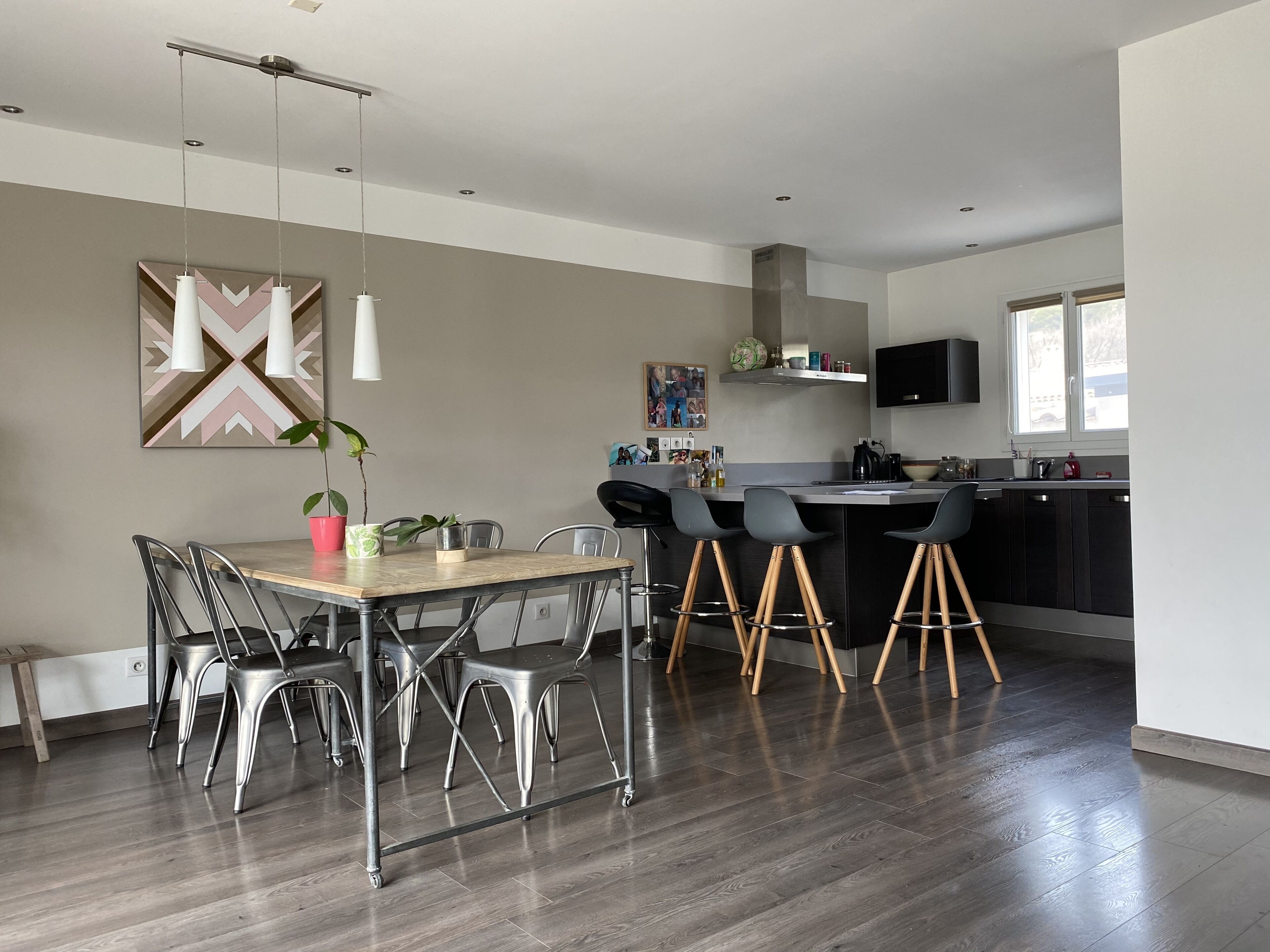 A modern kitchen with a dining area, featuring a wooden table, metal chairs, and a bar area with stools.