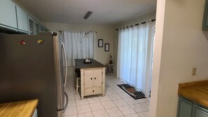 A compact kitchen with a refrigerator, a small dining table, and a cabinet. - Spacious South Venice Home (Venice)