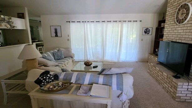 A living room with a sofa, coffee table, and a fireplace. - Spacious South Venice Home (Venice)