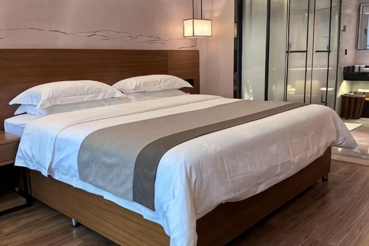 A neatly made bed with a wooden headboard, a bedside table, and a modern light fixture.