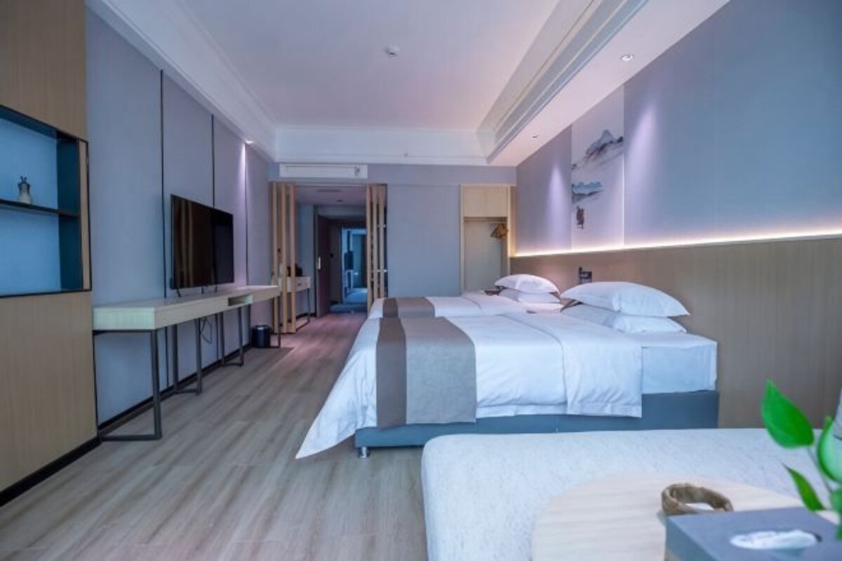 A hotel room with a bed, bedside table, TV, and a desk with a chair.